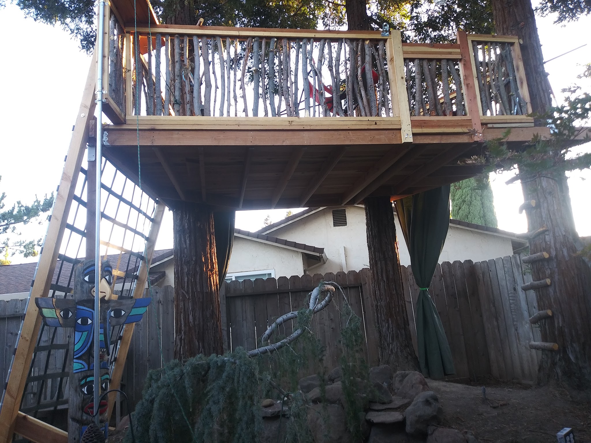 Custom elevated deck platform built between two large trees by Romack Home Maintenance
