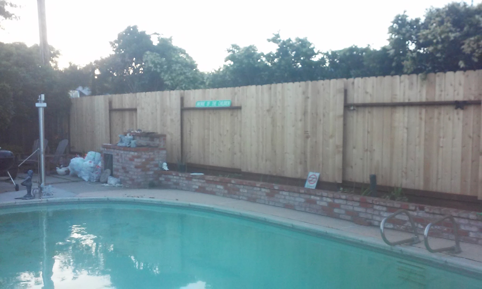 New wood privacy fence installed around a backyard pool by Romack Home Maintenance